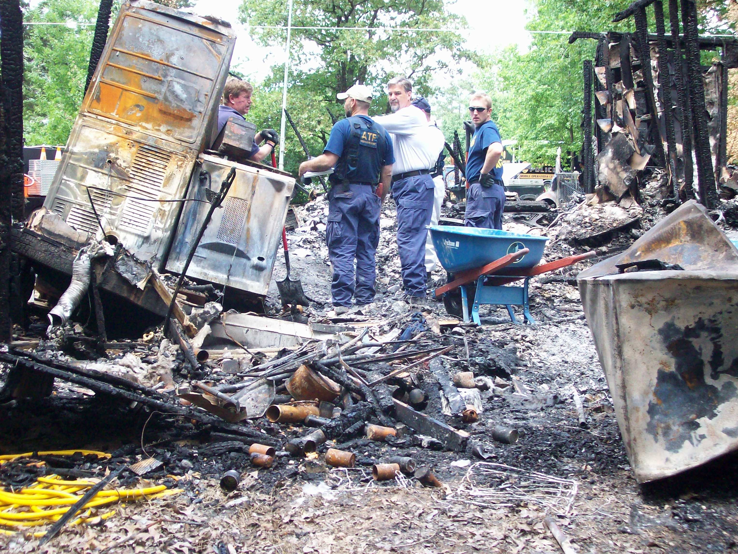 Fire fighters assess the damage from the fire, the house burned down to its frame.